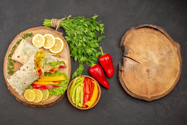 Top view of tasty shaurma sliced chicken sandwich with lemonnd greens on dark