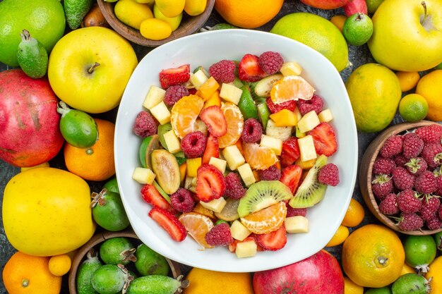 Top view tasty sliced fruits with fresh vegetables on gray background