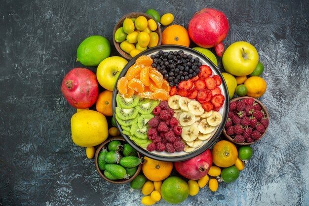 Top view tasty sliced fruits with fresh vegetables on gray background