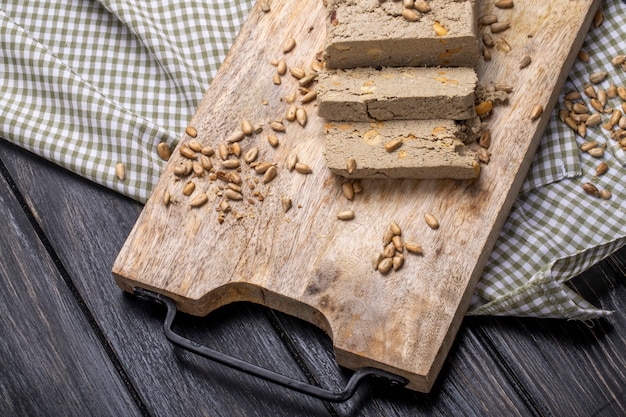 Top view of tasty slices of halva with sunflower seeds on a wooden board