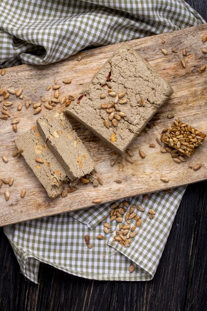 Top view of tasty slices of halva with sunflower seeds on a wooden board