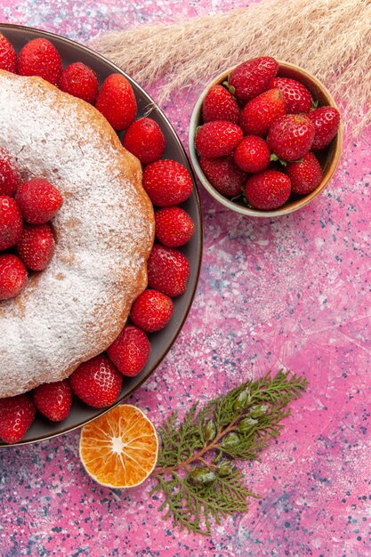 Вид сверху вкусный клубничный пирог с сахарной пудрой на розовом