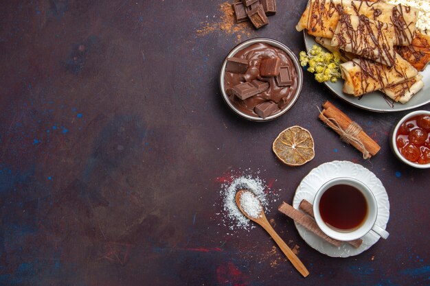 Top view tasty sweet pastries with cup of tea on dark background pastry biscuit cake sugar sweet tea cookie