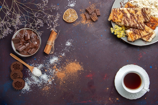 Top view tasty sweet pastries with cup of tea on dark background pastry biscuit cake sugar sweet tea