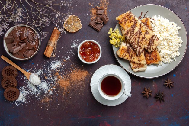 Vista dall'alto gustosi pasticcini dolci con tè e ricotta su sfondo scuro pasticceria biscotto torta zucchero tè dolce