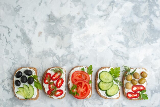 Top view tasty toasts with tomatoes olives and cucumbers on white background sandwich bread food meal burger horizontal