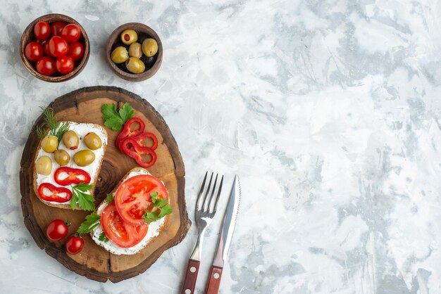 Top view tasty toasts with tomatoes and olives on wooden board white surface