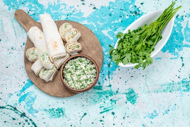 Foto gratuita vista dall'alto gustosi involtini di verdure intere e affettate con ripieno di verdure e insalata di cavolo sulla scrivania blu brillante cibo pasto rotolo pranzo vegetale