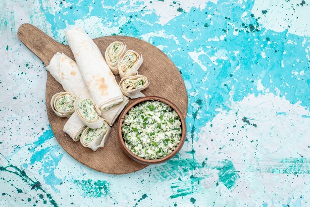 Top view tasty vegetable rolls whole and sliced with greens filling and cabbage salad on the bright-blue desk food meal roll vegetable snack lunch