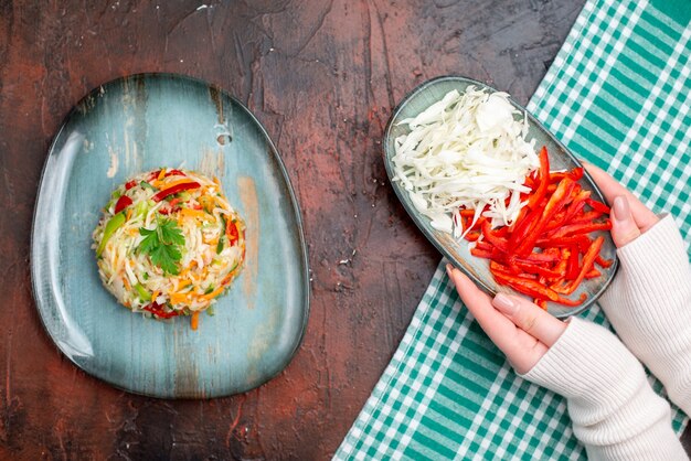 Top view tasty vegetable salad inside plate with sliced cabbage and bell-pepper on dark table