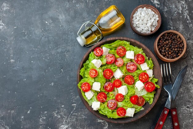 暗い背景にスライスしたチーズトマトと調味料を使ったトップビューのおいしい野菜サラダランチ健康食事食品カラーダイエット