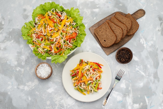 Top view tasty vegetable salad with sliced vegetables and green salad with bread loafs on grey, vegetable salad food meal