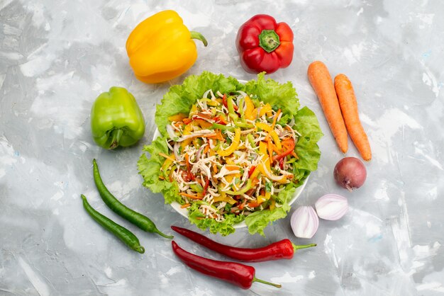 Top view tasty vegetable salad with sliced vegetables and whole fresh vegetables on grey, vegetable salad food meal