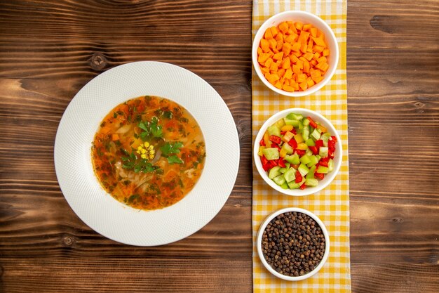 Вид сверху вкусный овощной суп с приправами на коричневом деревянном столе суп еда овощная приправа еда