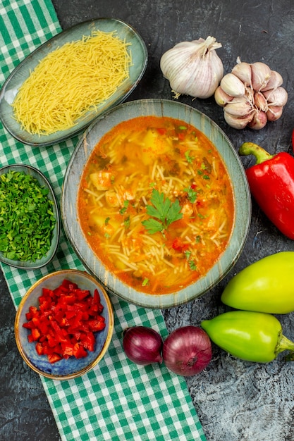Вид сверху вкусный суп из вермишели с чесночной зеленью и овощами на светло-сером столе