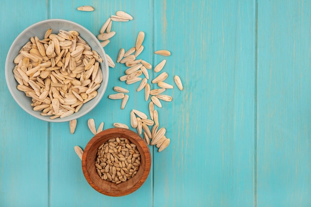 Top view of tasty white sunflower seeds on a bowl with shelled sunflower seeds on a wooden bowl with copy space