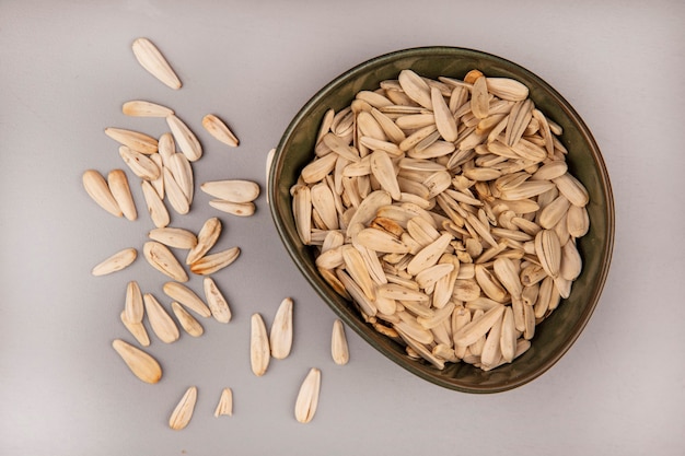Top view of tasty white sunflower seeds on a bowl with sunflower seeds isolated