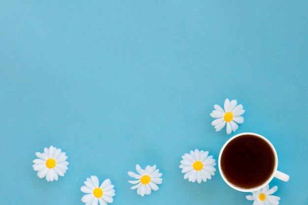 Top view tea cup surrounded by flowers with copy space