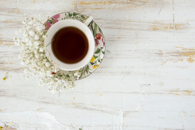 Top view of tea cup with flowers on wooden surface