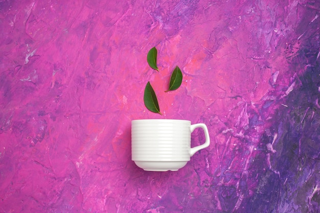 Вид сверху чайная чашка с листьями на розовом