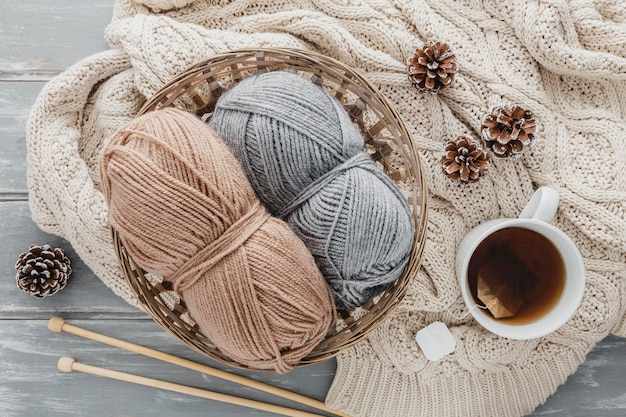 Top view tea mug and yarn in basket with pine cones