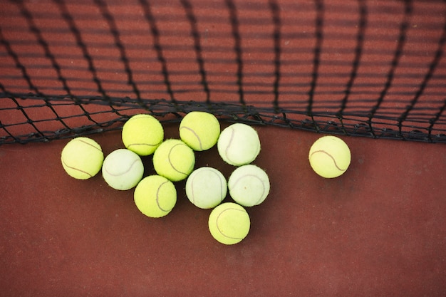 Foto gratuita palline da tennis di vista superiore accanto a rete sul campo