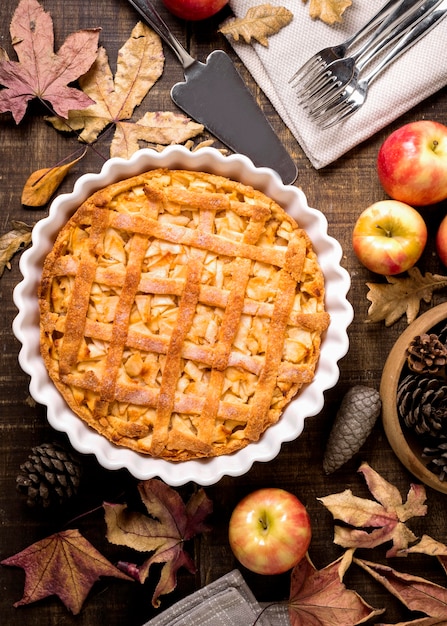 Top view of thanksgiving apple pie with autumn leaves and pine cones