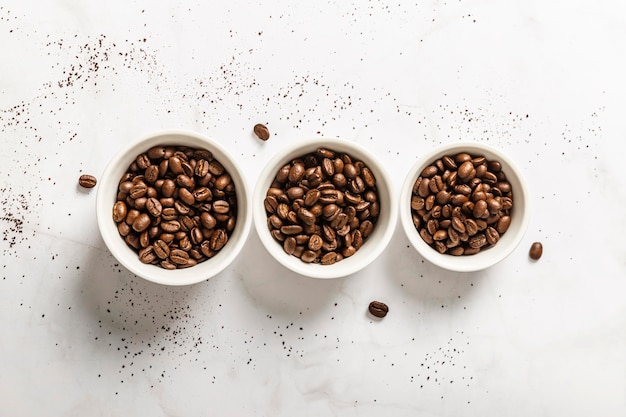 Top view of three cups with roasted coffee beans