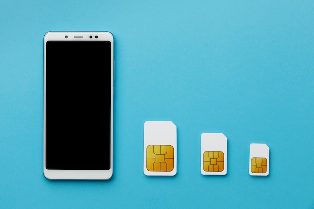 Top view of three sim cards with smartphone and copy space
