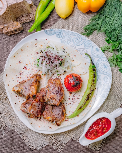 Top view tika kebab on pita bread with tomato and green pepper grilled with herbs and onions