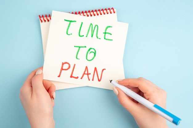 Top view time to plan written on sticky note in female hands on blue table