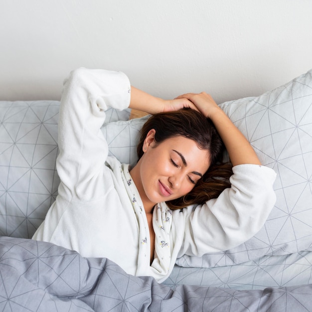 Top view of tired woman in bed wearing pajamas