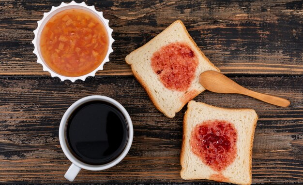 Top view of toasts with jam and coffee on dark wooden surface horizontal