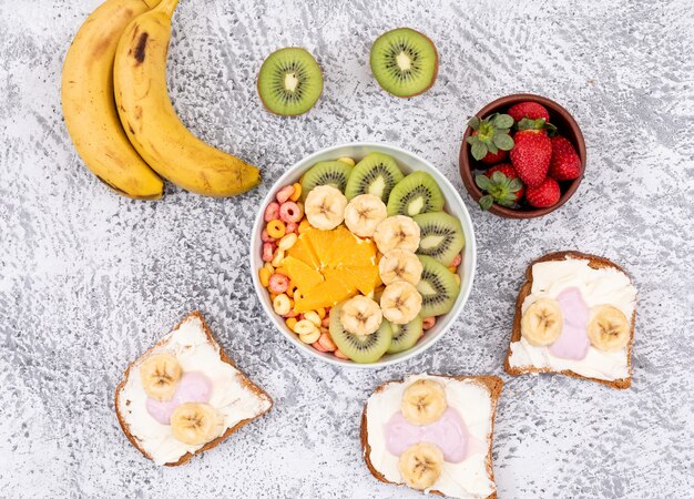 Top view of toasts with yogurt and fruits on white surface horizontal