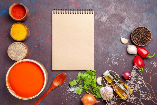 Top view of tomato soup cooked from fresh tomatoes with different seasonings on black