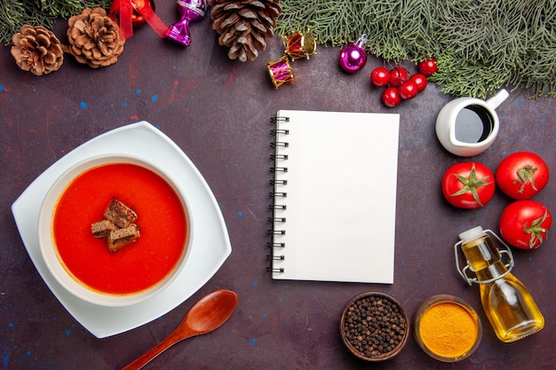 Top view of tomato soup with fresh tomatoes and seasonings on black table