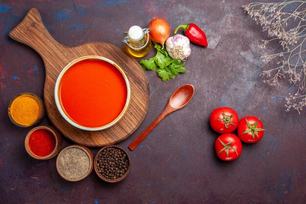 Vista dall'alto della zuppa di pomodoro con condimenti sul tavolo nero