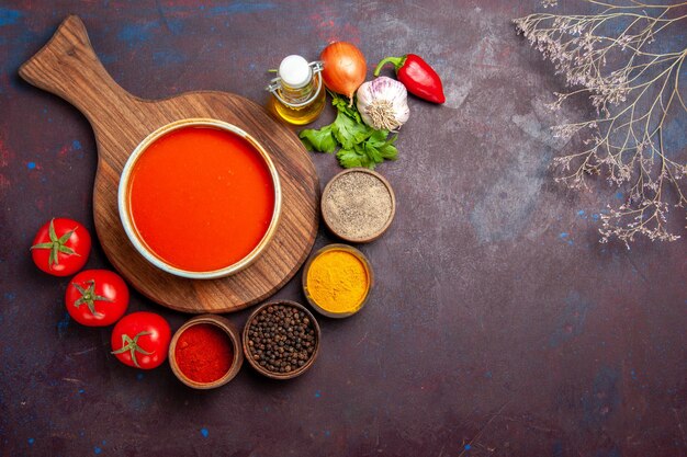 Top view of tomato soup with seasonings on black