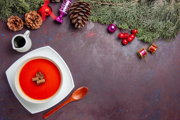 Top view of tomato soup with sliced bread inside on black