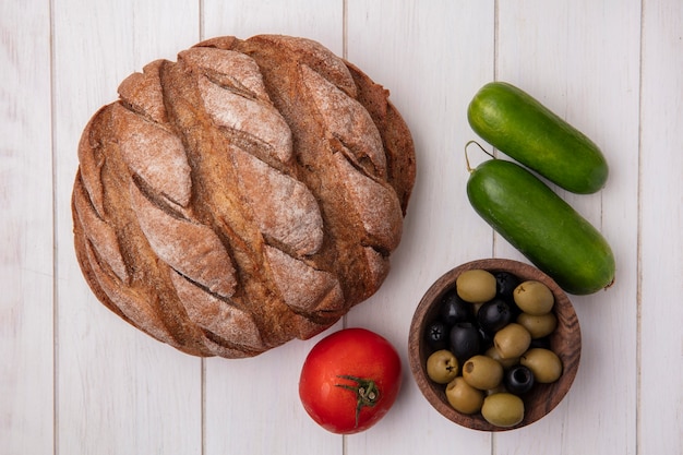 Foto gratuita vista dall'alto pomodoro con cetrioli pagnotta di pane integrale e olive su sfondo bianco