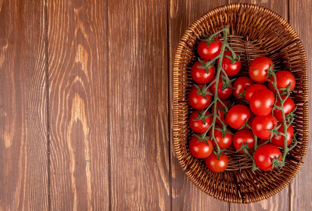 Top view of tomatoes in basket on right side and wood with copy space