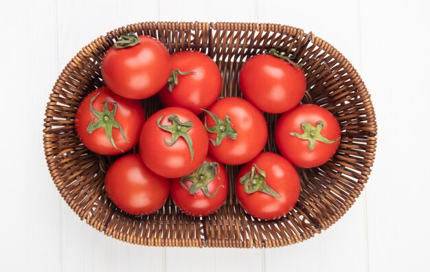 Top view of tomatoes in basket on white surface