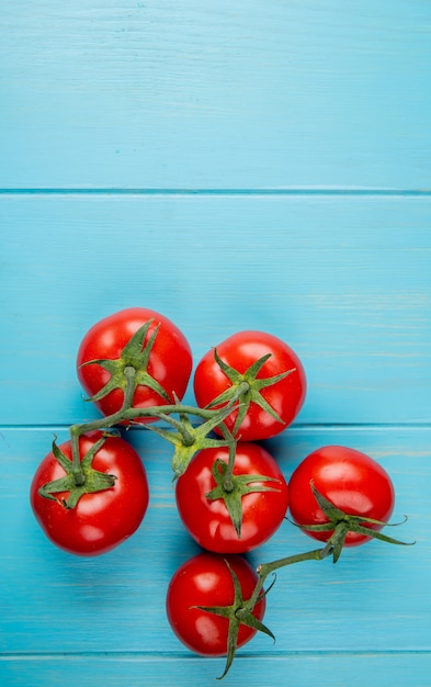 Top view of tomatoes on blue surface with copy space