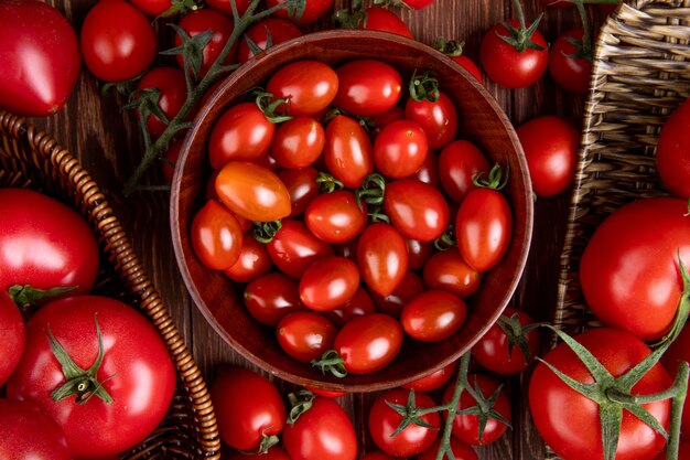 Top view of tomatoes in bowl basket and plate on wooden surface