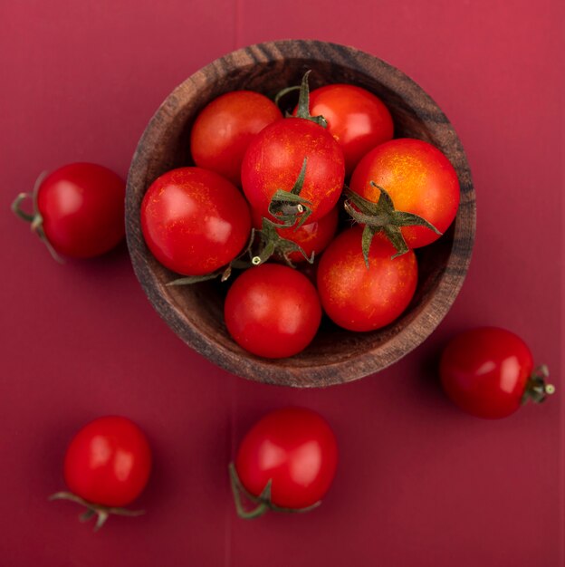 Top view of tomatoes in bowl and on red surface