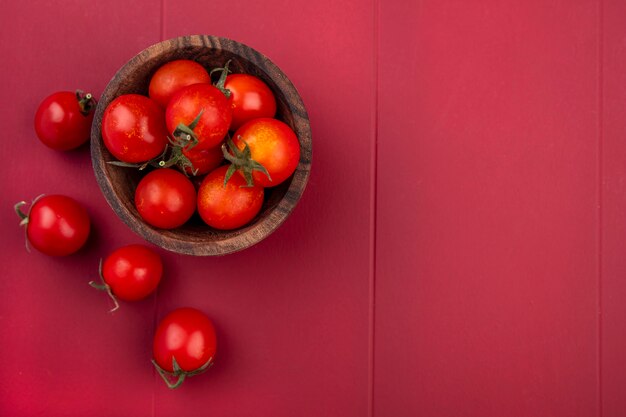 Top view of tomatoes in bowl and on red surface