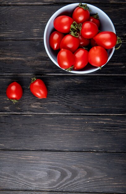 Top view of tomatoes in bowl on wooden surface with copy space