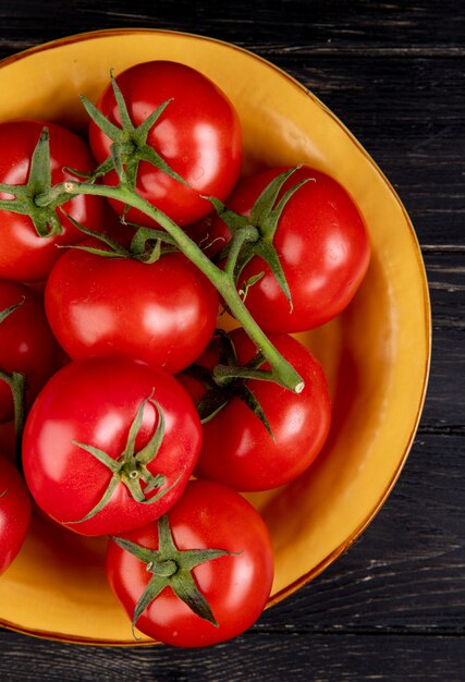 Top view of tomatoes in bowl on wooden surface