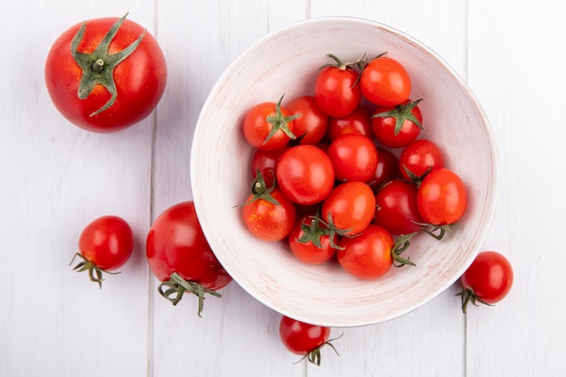 Top view of tomatoes in bowl and on wooden surface