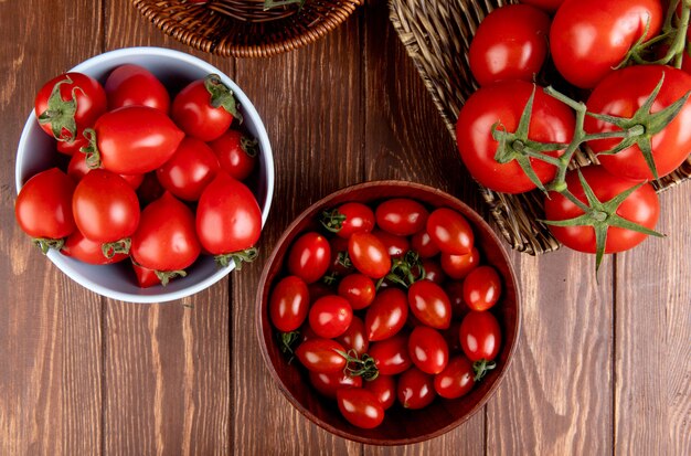 Top view of tomatoes in bowls and basket plate on wooden surface